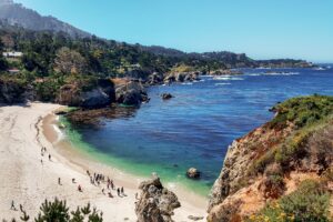Rocky coastline near Carmel-by-the-Sea with a sandy cove, blue Pacific water, and coastal bluffs